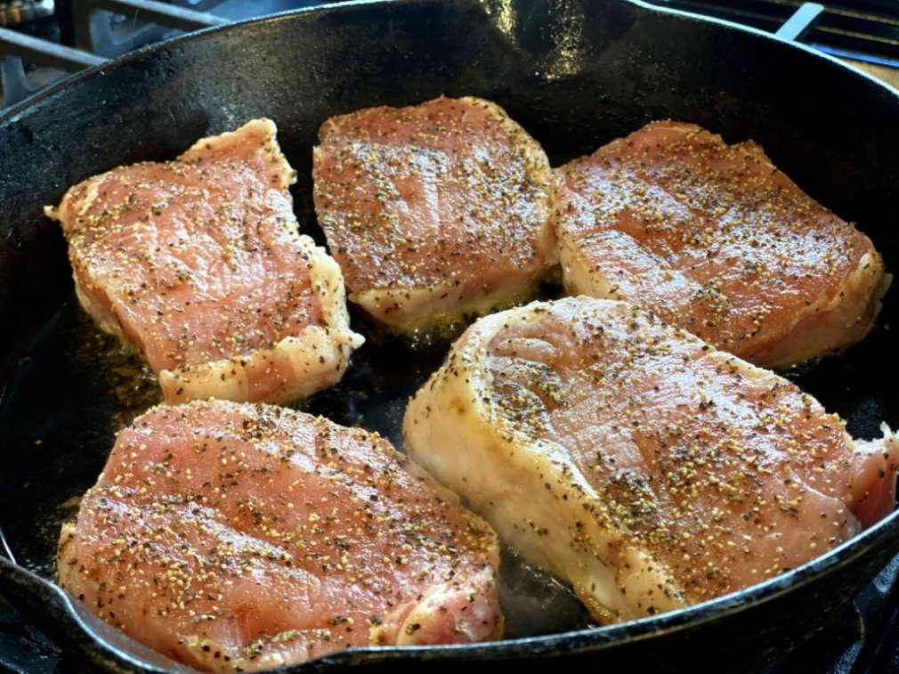 Cooking pork chops in a cast-iron skillet. 