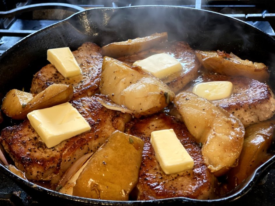 Pats of butter melting on the top of each pork chop with baked pears. 