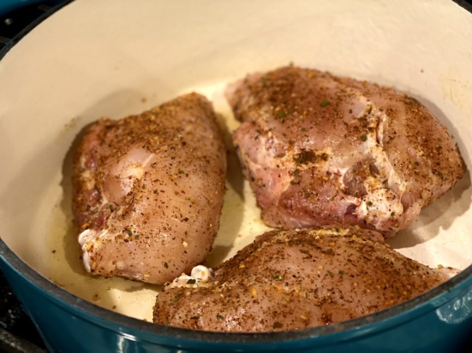 Cooking chicken breasts in a blue Dutch oven. 