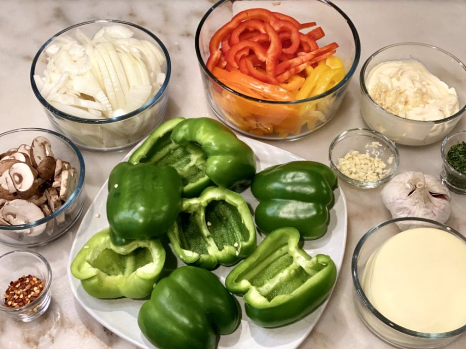 Ingredients needed for Cheesesteak Stuffed Peppers including mushrooms, onions, peppers, garlic, herbs, seasonings, and aioli sauce.