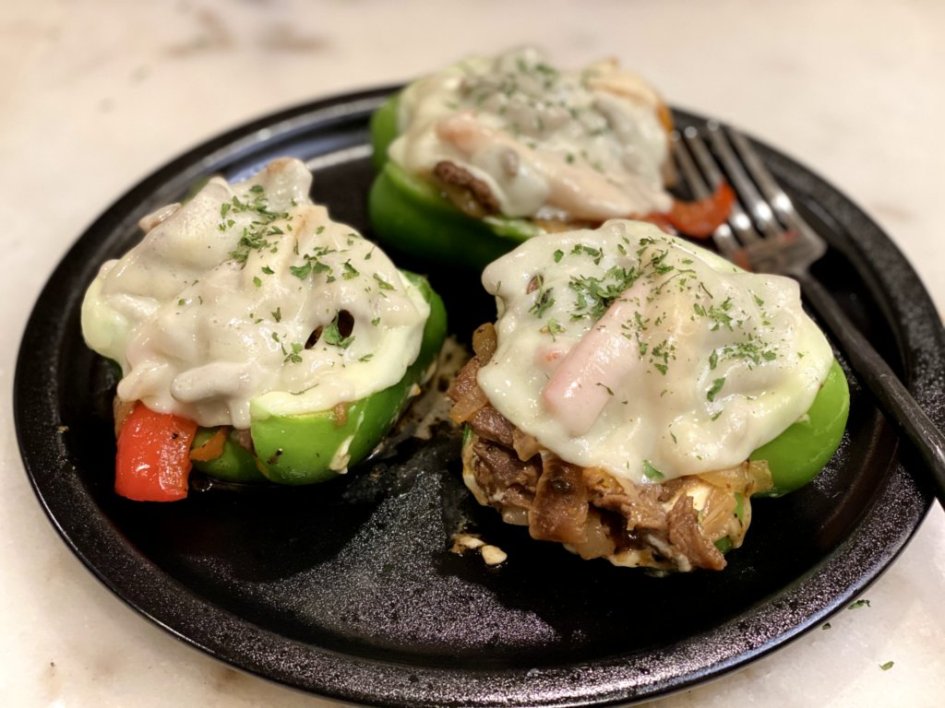 Philly Cheesesteak Stuffed Peppers with melted cheese on a black plate. 
