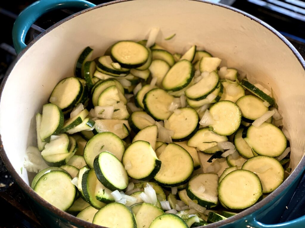 Chopped onions, sliced zucchini, and seasonings in a Dutch oven cooked in chicken broth. 