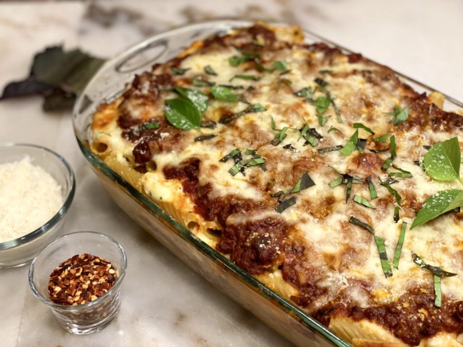 Lasagna-Style Creamy Baked Pasta in a glass baking dish with parmesan and red pepper flakes on the side.