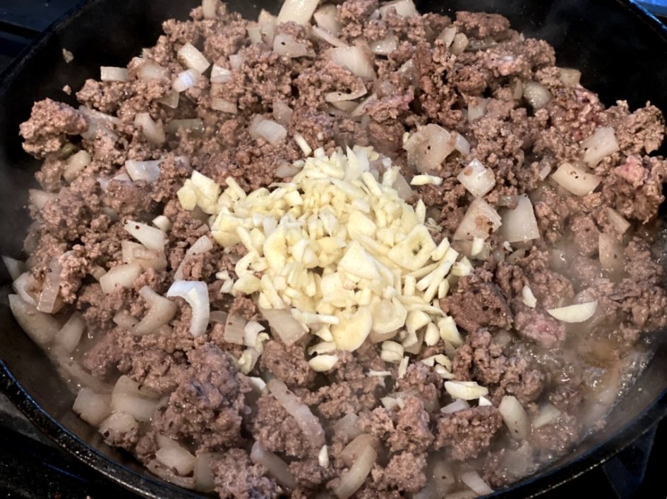 ground beef browned in a cast iron pan with onions and garlic