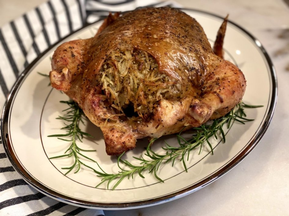 potato stuffed chicken on a platter with fresh rosemary sprigs