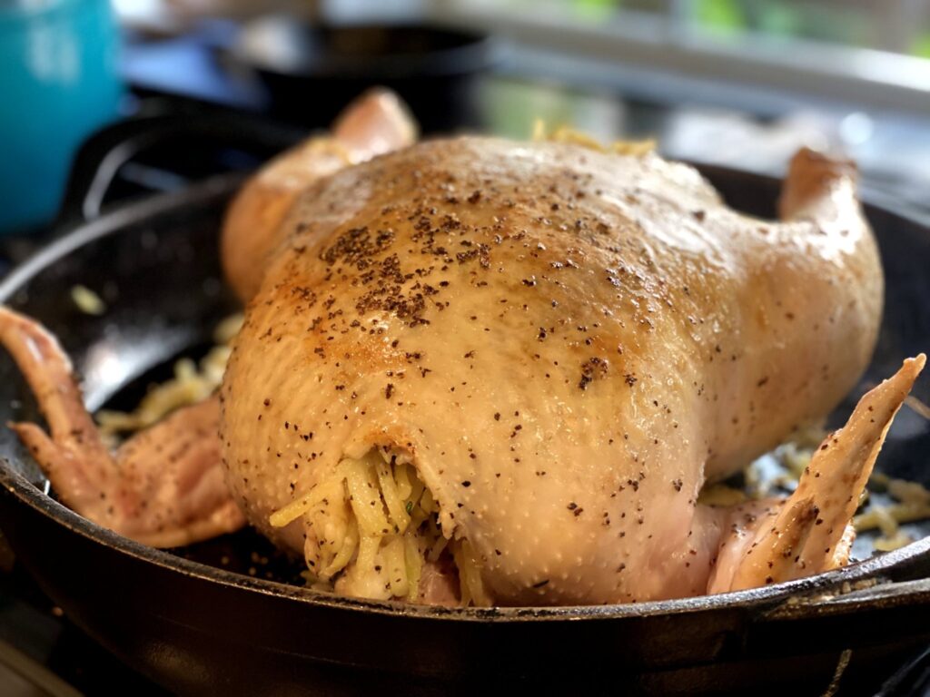 Browned whole fryer chicken in a large skillet