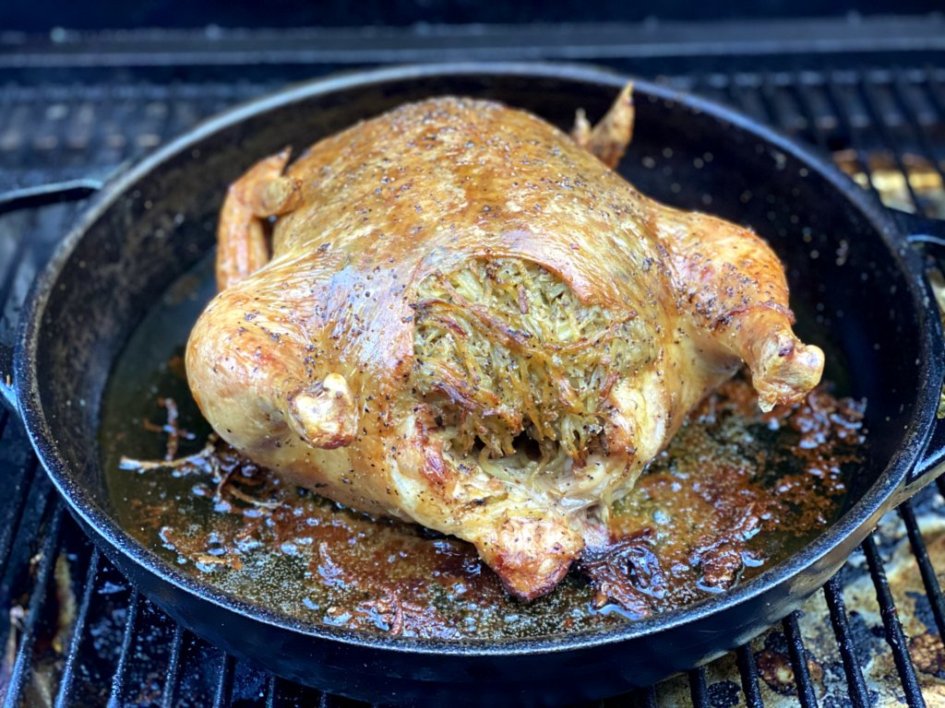 Roasting a whole chicken on a traeger grill with lots of pan juices and brown bits. 