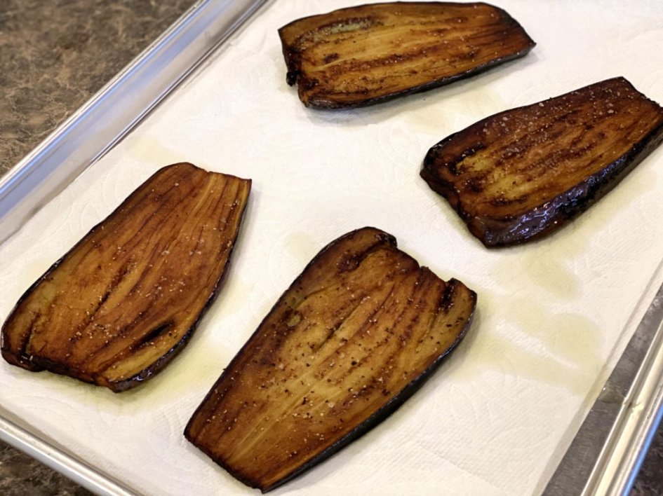 Browned eggplant drying on a baking sheet pan. 