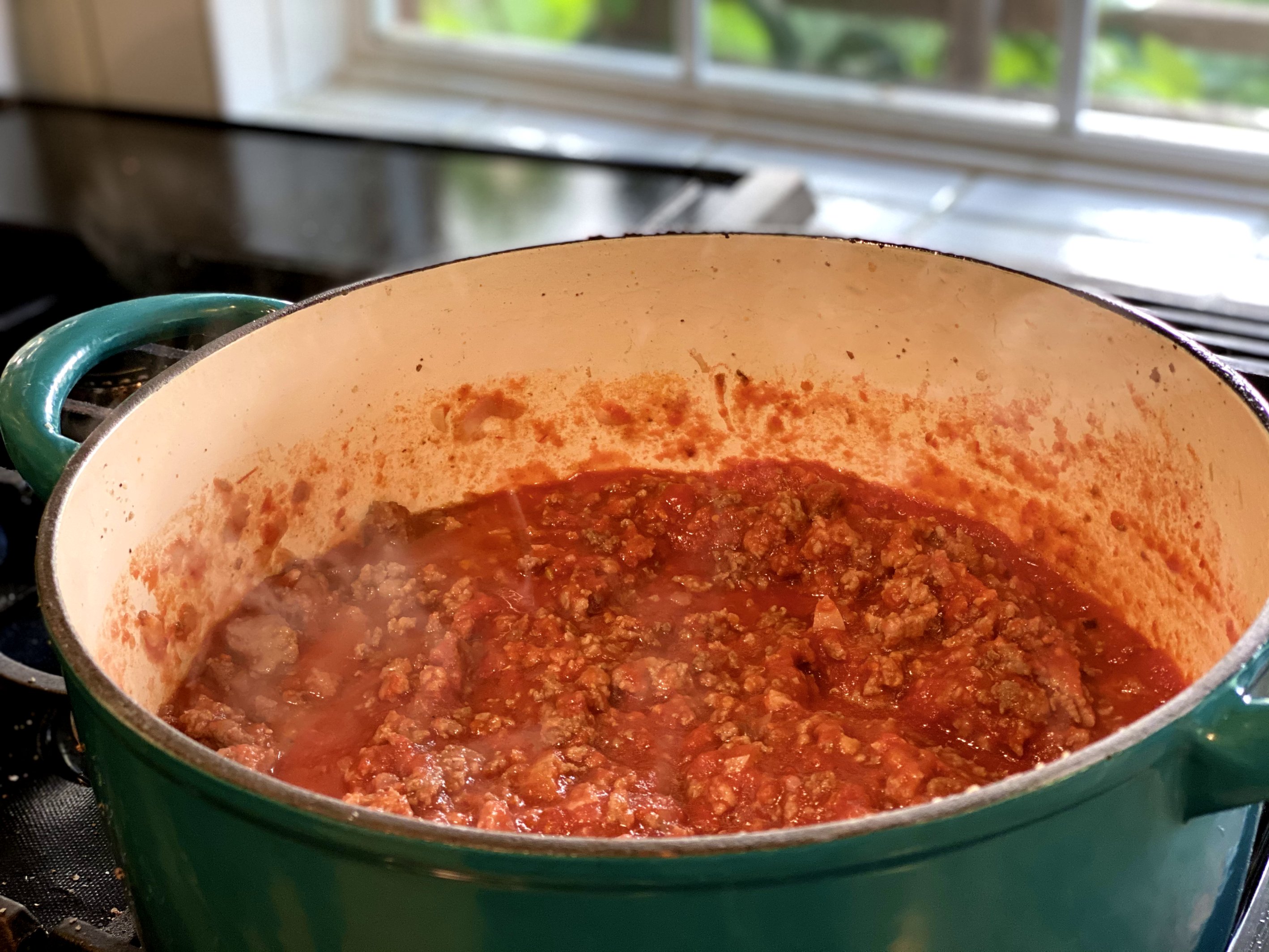 Delicious meat sauce with ground beef, Italian sausage, and tomatoes in the Dutch oven. 