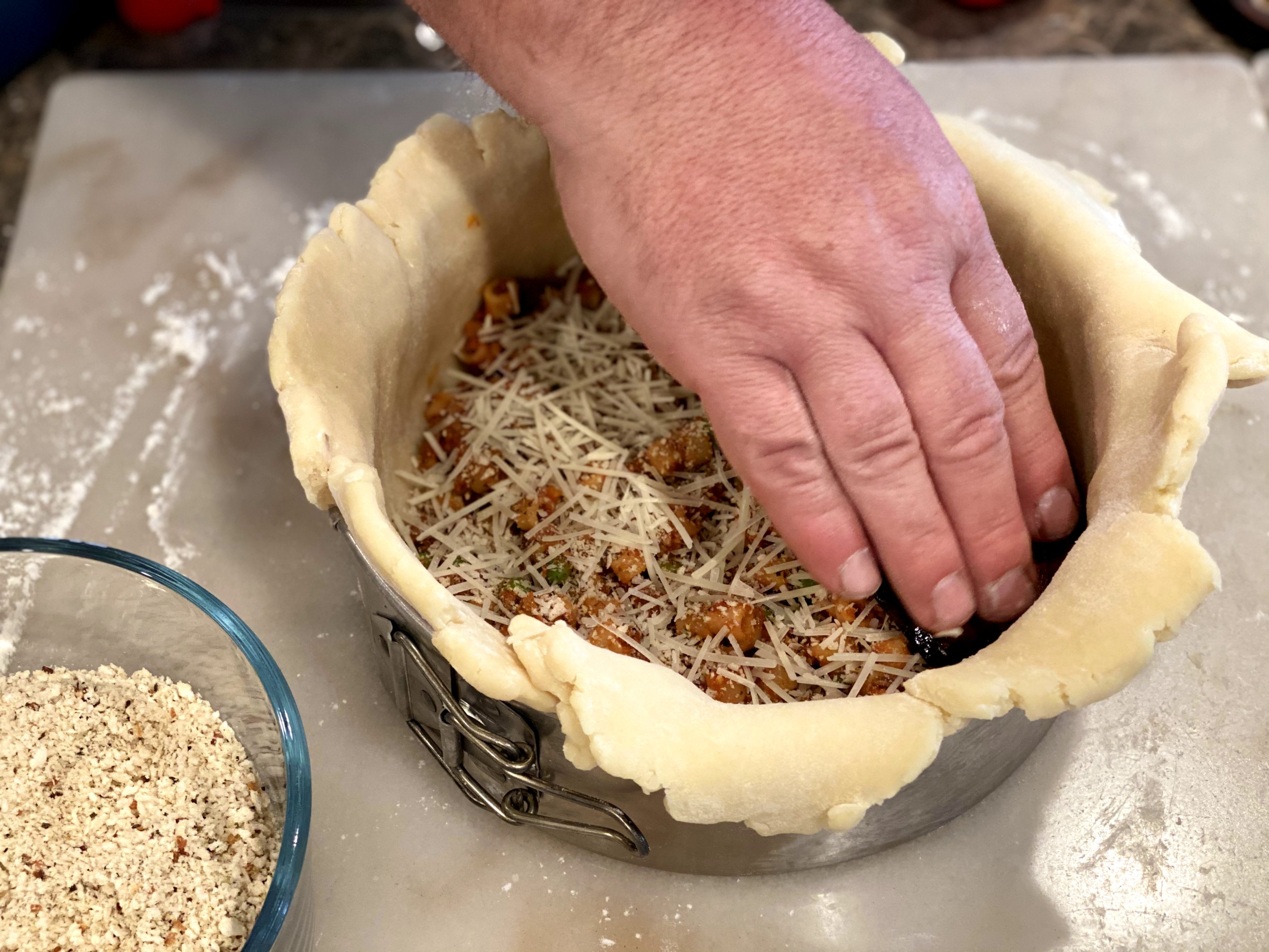 Adding layers of parmesan cheese to the timballo.