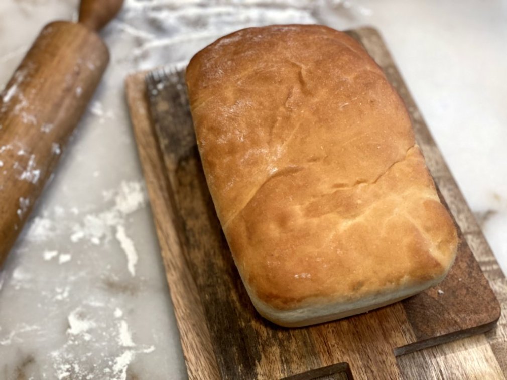 delicious homemade breads on a wooden cutting board with a floured rolling pin,