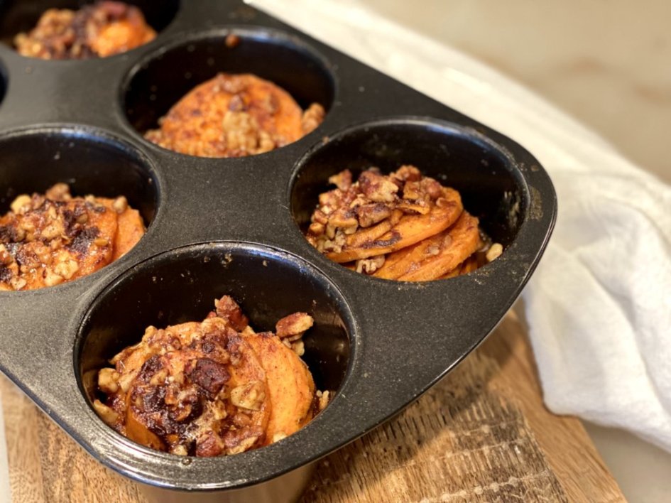 Maple Pecan Sweet Potato Stacks with pecans, walnuts, and hazelnuts, sweetened with brown sugar and maple syrup baking in a muffin tin. 