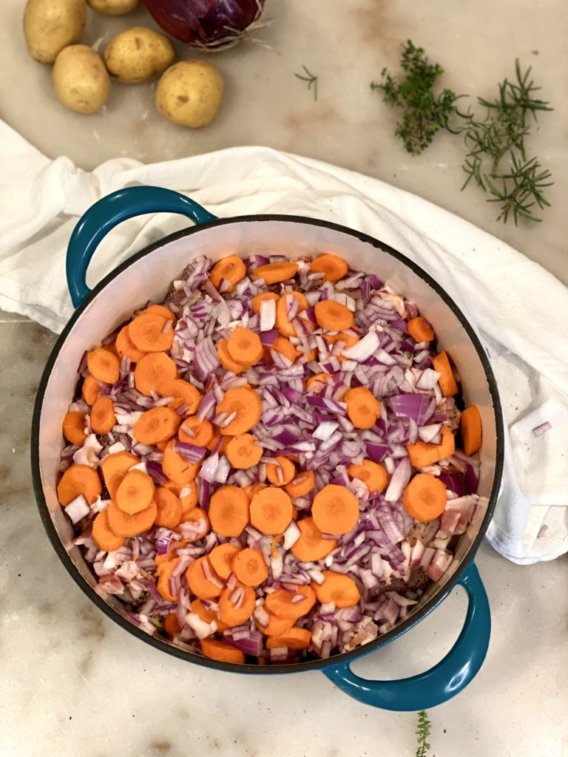 chopped carrots and diced onions in a blue pot to make country chicken hotchpotch.