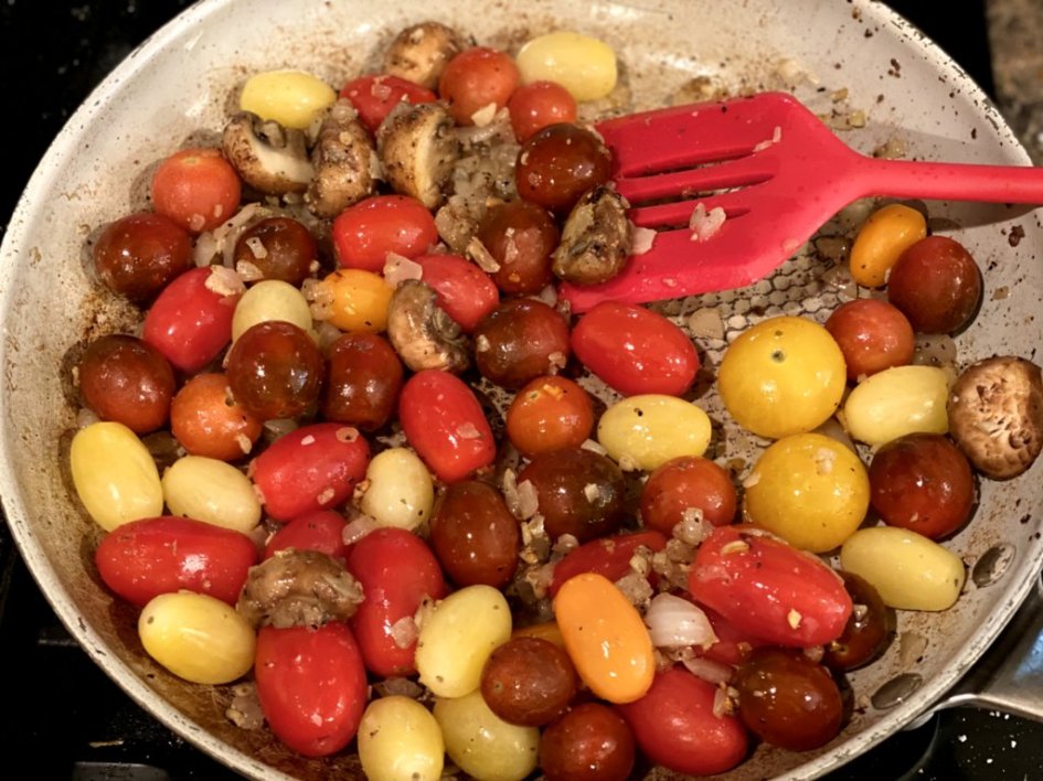 roasting tomatoes in a pan with olive oil, garlic, onions, and mushrooms. 