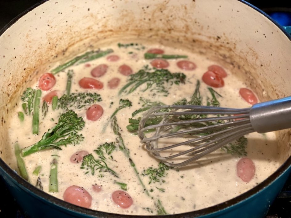 sautéing the vegetables in the cream sauce in a blue dutch oven 