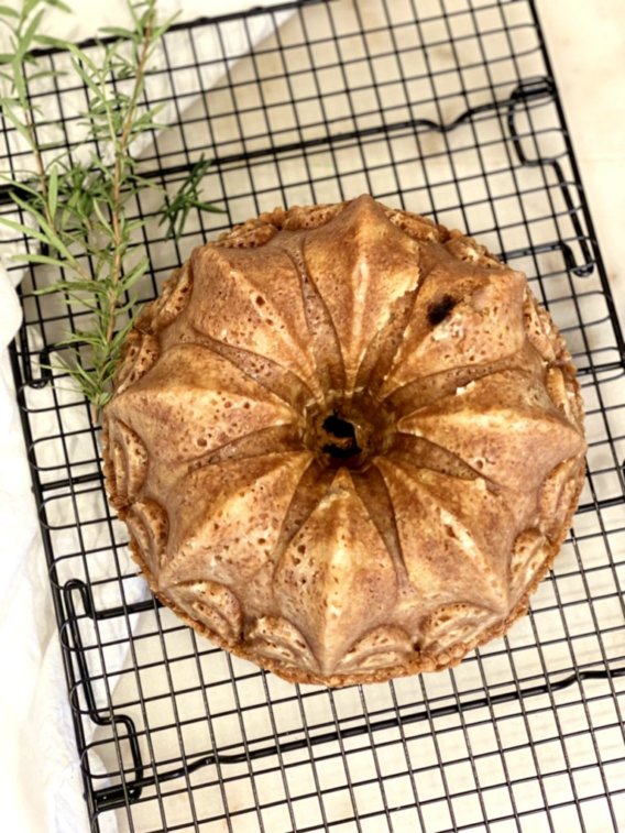 easy bundt cake recipes. cake cooling on a black cooling rack with rosemary sprigs in the background.