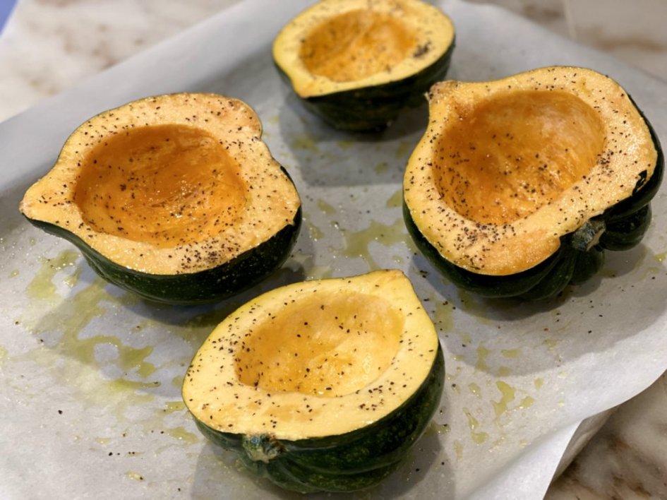 acorn squash cut in half with the seeds scooped out and seasoned with salt and pepper.